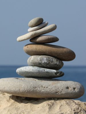 a tall stack of smooth rocks all balancing on one another, in front of the ocean