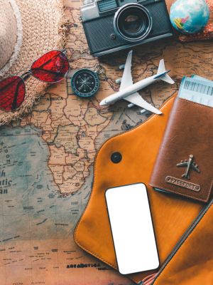 image collage of travel items including a passport, sunglasses, camera, plane, compass, and map