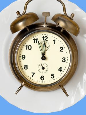 Alarm clock on a plate to signify intermittent fasting