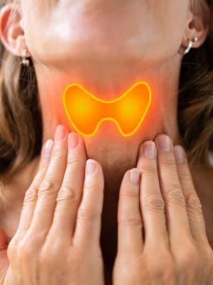 woman touching her neck and thinking about her autoimmune thyroid diagnosis