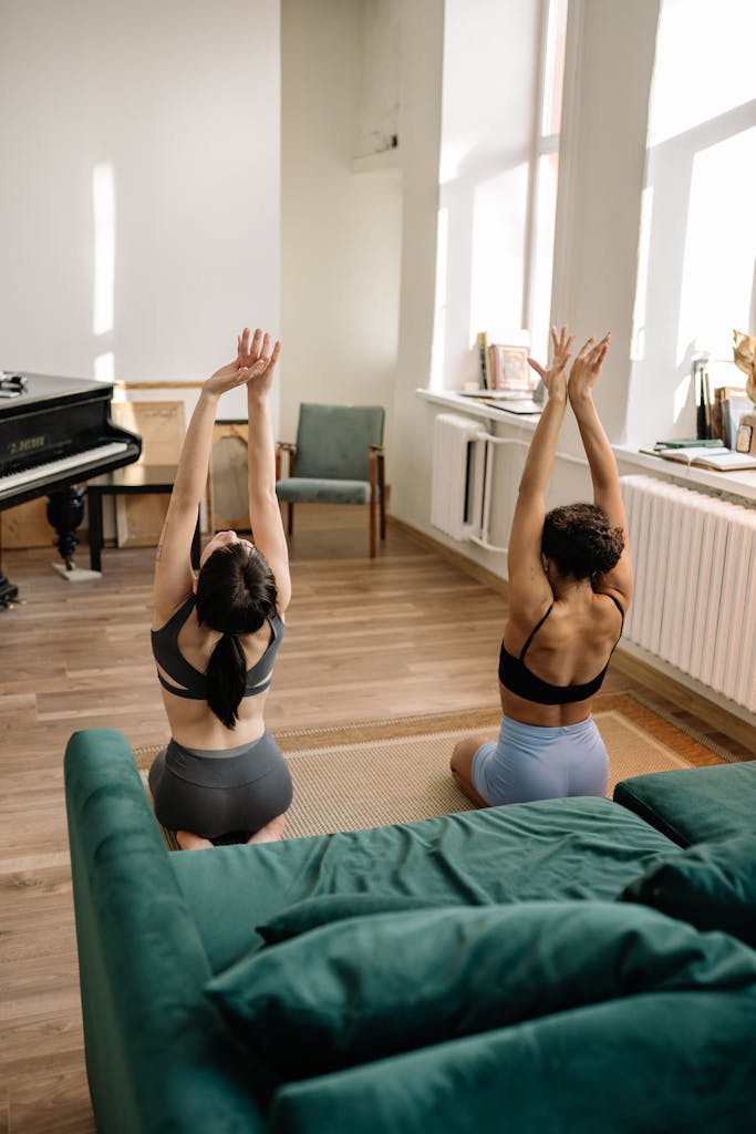 Two women in sportswear performing yoga in a cozy living room.